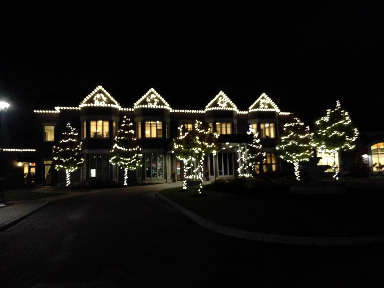 Commercial building roofline with permanent RGBW LED lighting glowing in warm white above a hotel entrance at dusk in winter