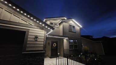 Home outlined in warm white permanent LED roofline lighting at night