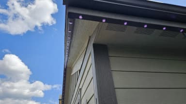 RGBW puck lights in black aluminum track under an eave