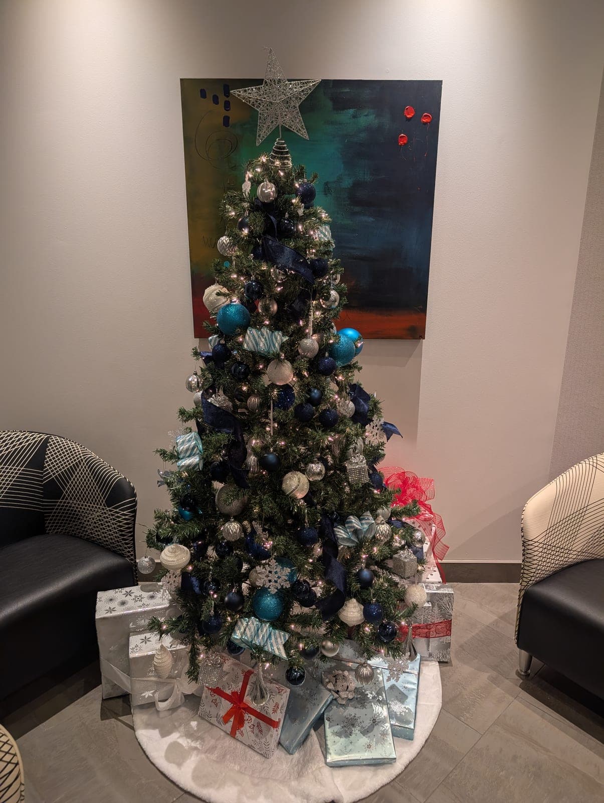 Blue and silver ornament Christmas tree with presents in a corporate reception area
