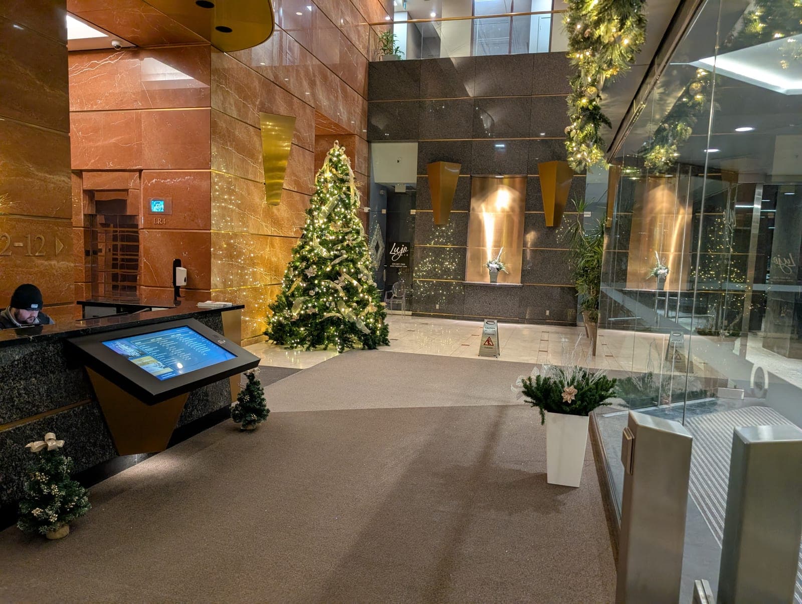 Elegantly decorated Christmas tree and lit garland in a corporate office building lobby at night.